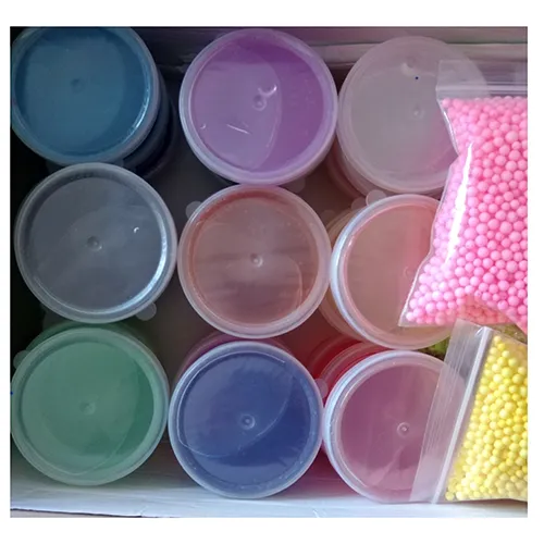 Toy slime in various colours in plastic pots with plastic lids. The set also includes bottles of glitter in a variety of colours, as well as small colourful balls and pink mixing tools.