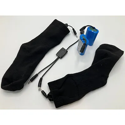 A pair of black tight-knit socks, fitted with bulky, lithium battery powered electronics.