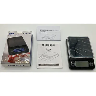 Small (6.8x10x2 cm) digital scale with a black plastic exterior, transparent weighing plate cover, LCD display and a pair of buttons.