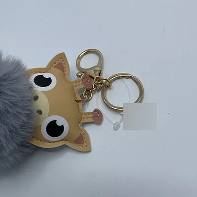 Plush toy, in the shape of a giraffe head and a grey pom pom, with keychain.