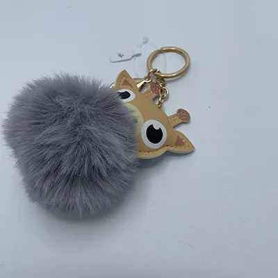 Plush toy, in the shape of a giraffe head and a grey pom pom, with keychain.