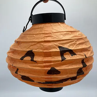 Orange lantern, reminiscent of a Halloween pumpkin. 20 cm in diameter with black plastic details.