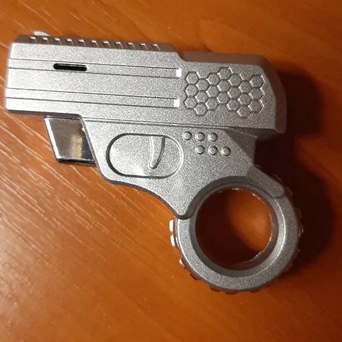 Lighter in the shape of a small pistol. The part that is usually the magazine (the part that the pistol is held by when firing) is in the shape of a circle. The trigger of the pistol is the operating button. When pressed, a flame shoots out of the barrel of the pistol.