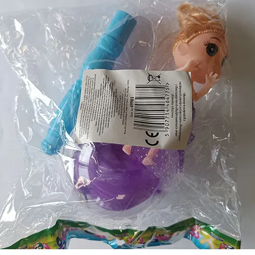 Plastic doll in a purple textile dress. The doll's legs are placed in a transparent plastic ball with feathers. A controller, including a battery, is attached to the doll’s head.