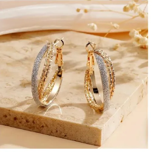 Pair of crossed hoop earrings made of gold-coloured metal with a non-metallic strip of glitter glued to one ring. All batches are concerned. Product sold online, in particular via TEMU (unique product identifier: 601099582004796).