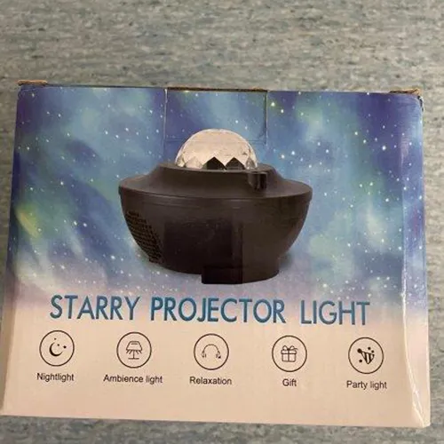 Projector light in the form of moving galactic nebulae and a starry sky. The galactic nebulae are projected via a transparent crystalline hemisphere in the upper part of the projector. Product sold online, in particular via Kaufland.de