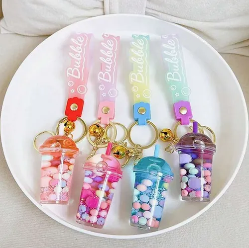 Three keyrings with a bubble tea cup figure. The plastic figure contains two non-mixable liquids (pink and clear) in containers sealed by a rubber plastic stopper. Product sold online, in particular via Shein (product identifier, SKU: sc2407277808880181).