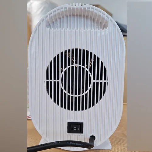 Oval-shaped white fan heater with a black grille and a black power cord attached. Product sold online, in particular via Amazon (ASIN: B0CMCZT6QR).
