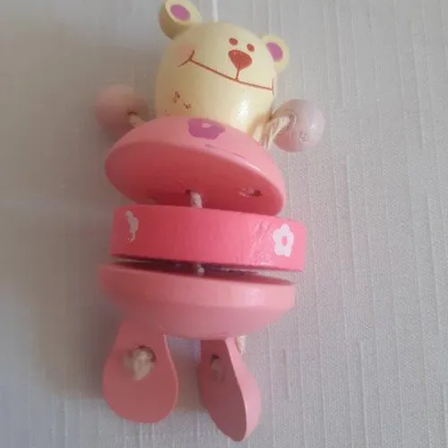 Wooden pink crib toy with five teddy bear figures.