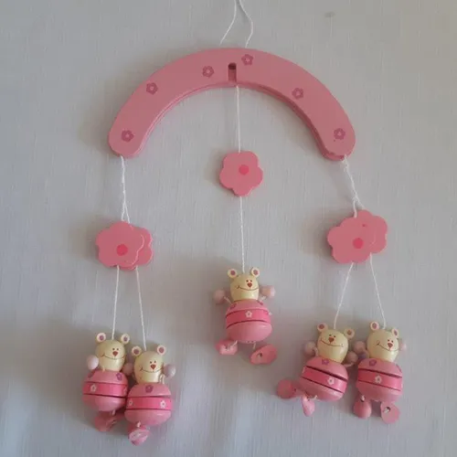 Wooden pink crib toy with five teddy bear figures.