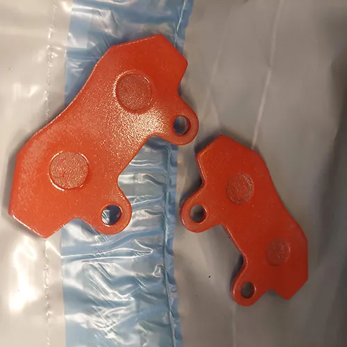 Orange-coloured brake pads. Product sold online, in particular via AliExpress.