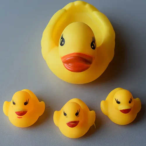 Yellow plastic toy duck family consisting of one larger and three smaller squealing ducks.