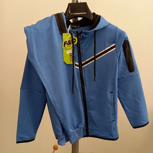 Children's clothing set intended for young children, made of light blue textile knit material. It is composed of a jumper with hood, zipper and inset pockets. The hood has a drawstring functional textile cord with free ends about 24 cm long. It also includes a pair of trousers made of light blue textile knit material and with inset pockets.