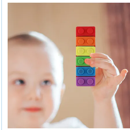 Teether in the shape of a toy construction brick with a cord and detachable parts. Product sold online, in particular via eBay (unique identifer: 167636875338).