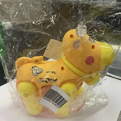 Plastic battery-operated, has wheels and an attached string. The toy is in the shape of a cow, with painted eyes and cheeks, horns, and a transparent bell attached to the neck.