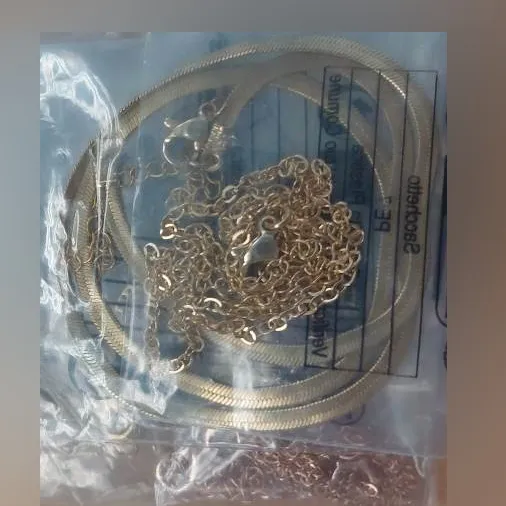 Set of six necklaces. One copper-coloured metal necklace with an imitation gemstone charm. One golden metal necklace with an imitation gemstone charm. One golden, simple metal chain. One golden flat link chain. One golden metal necklace with a heart charm. Product sold online, in particular via Temu.