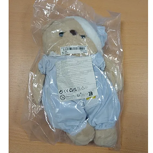 Soft toy in the shape of a bear with black plastic eyes, dressed in blue pyjamas and a matching nightcap. Product sold online, in particular via TikTok.