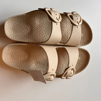 Tan sandals in PVC. The sandal has two straps with buckles.