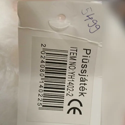 White plush toy in the shape of a bear with a red collar studded with bone-shaped studs.