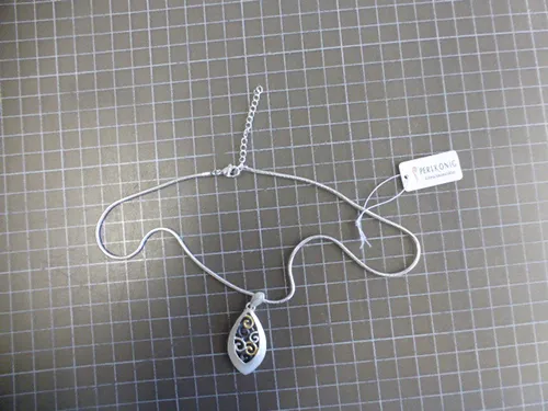 Silver-coloured metal necklace with silver, black and gold-coloured metal pendants, a closure and a chain extender.