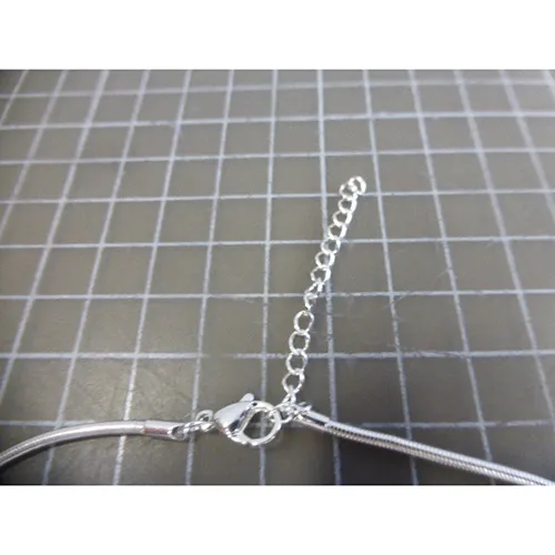 Silver-coloured metal necklace with silver, black and gold-coloured metal pendants, a closure and a chain extender.