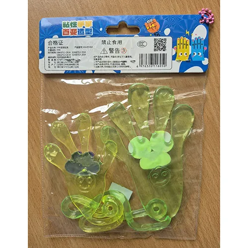 Plastic toy, yellow and green elastic adhesive hands with faces and strings ending in loops.