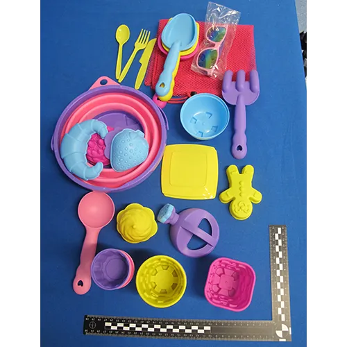 Plastic toy set intended for the beach consisting of 31 parts including a foldable bucket, set of cutlery (knives, forks and spoons), a net, sunglasses, a watering can, five tools, two plates and 17 moulds. Product sold online, in particular via Amazon (ASIN B0DSVW25YQ).