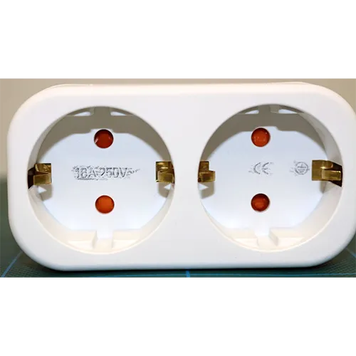 Double socket adaptor. Dimensions: height x width x depth = approximately 100 mm x 45 mm x 40 mm + base.
