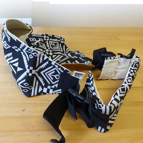 Baby carrier made from white fabric with black patterns and a plastic fastener.