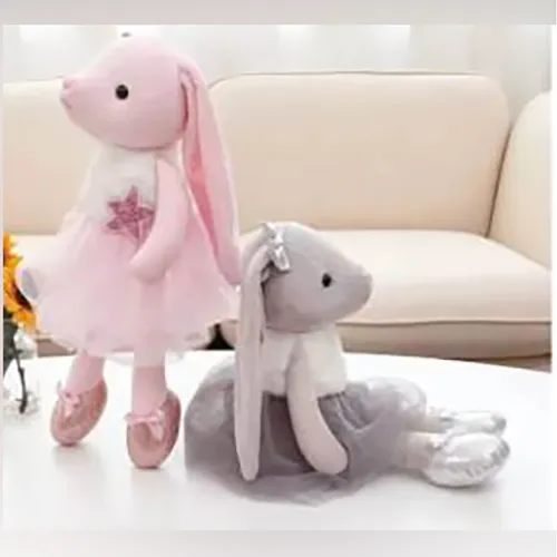 Soft toy, in the shape of a pink rabbit with long green and pink ears, wearing a pink dress.