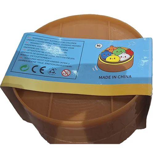Squeeze toy in the shape of a Chinese dumpling in a plastic container made to resemble a bamboo steamer.