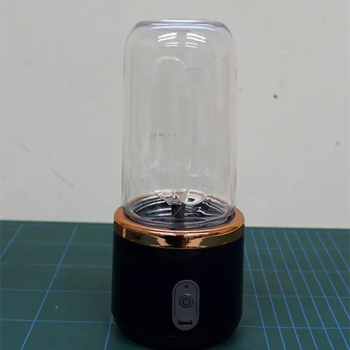 Portable juicer consisting of a plastic cylinder, the cutting unit, and a USB cable.