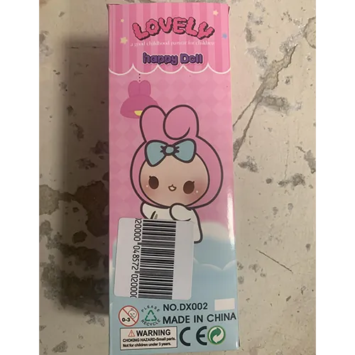 Plastic doll, with pink synthetic hair, wearing a textile hat with decorative ears, and dressed in pink clothes.