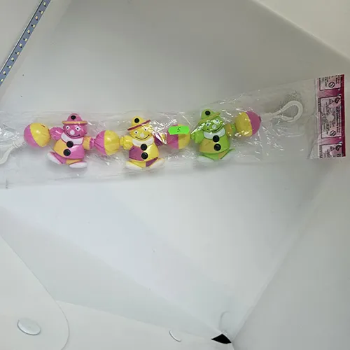 Toy rattle intended for babies that can be hanged. It consists of three different coloured man figures strung on a rope, with coloured plastic balls between them.
