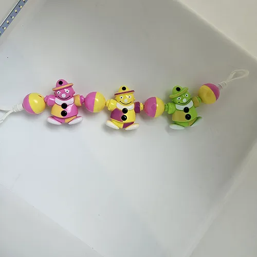 Toy rattle intended for babies that can be hanged. It consists of three different coloured man figures strung on a rope, with coloured plastic balls between them.