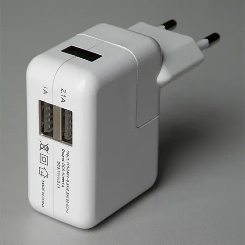USB charger with plastic housing, featuring two USB-A ports and a detachable mains plug.