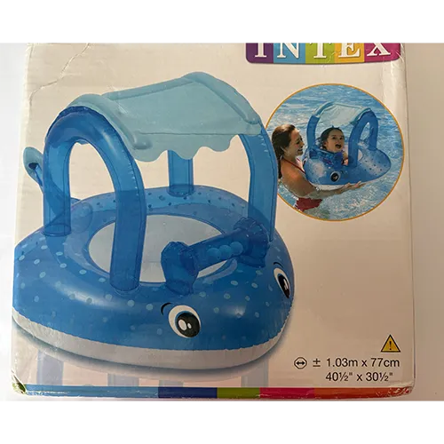 Blue inflatable swim seat with canopy, in the shape of a fish with a roof structure. Several balls with bells are integrated into the front area above the fish’s head.