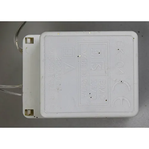 Decorative luminaire in the shape of a reindeer with yellow LED lights, gold-coloured glitter body, transparent insulated wires, and a white electronic controller box marked EK-04. Product is supplied with a cord extension set.