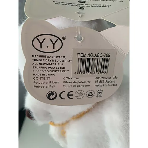 Soft white plush teddy bear made of textile material and filled with soft stuffing. It has a brown nose, decorative paw markings, and a yellow knitted scarf tied around its neck.