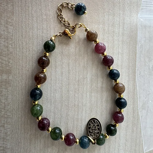 Rosary bracelet with brown-green-blue-coloured beads and a round metal pendant, sold in bulk.