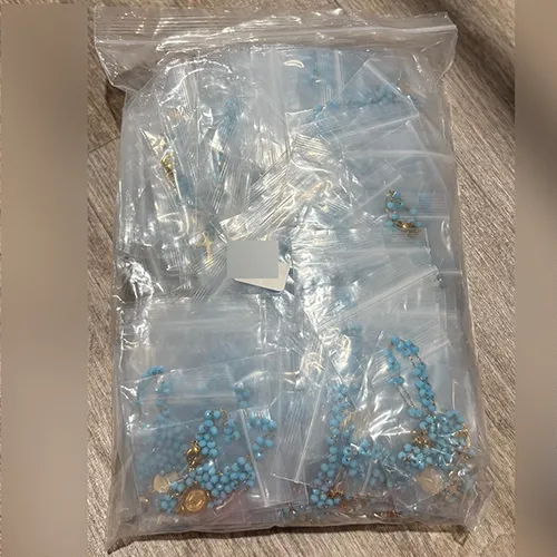Rosary necklace with turquoise-coloured beads, a round metal pendant, and a metal cross, sold in bulk.