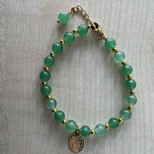 Rosary bracelet with green-coloured beads and a round metal pendant in between the beads, sold in bulk.