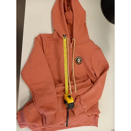 Set of a hooded sweatshirt and trousers, intended for children, size: 134 cm, made of light pink knitted textile fabric. The sweatshirt has an inscription on the front and functional drawstrings with loose ends, which are approximately 27 cm in length.