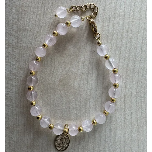 Rosary bracelet with pink-coloured beads and a round metal pendant.